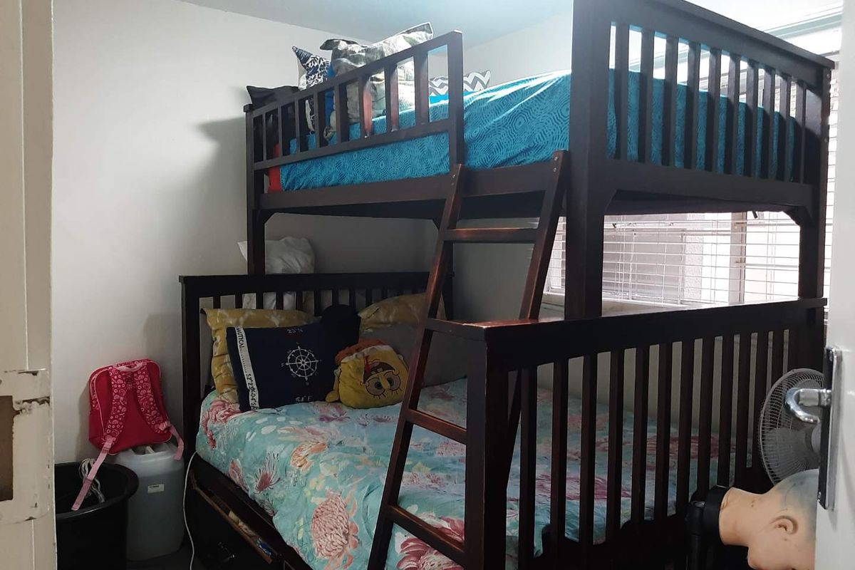 A compact bedroom featuring a window with venetian blinds and a door frame showing signs of wear.