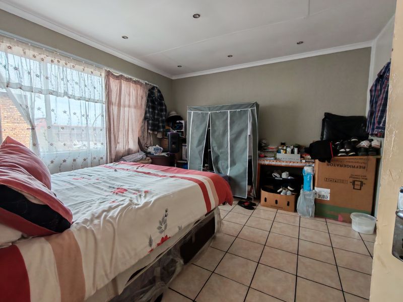 A bedroom featuring tiled flooring and recessed downlighting, offering a functional space that would benefit from cosmetic updates and decluttering.