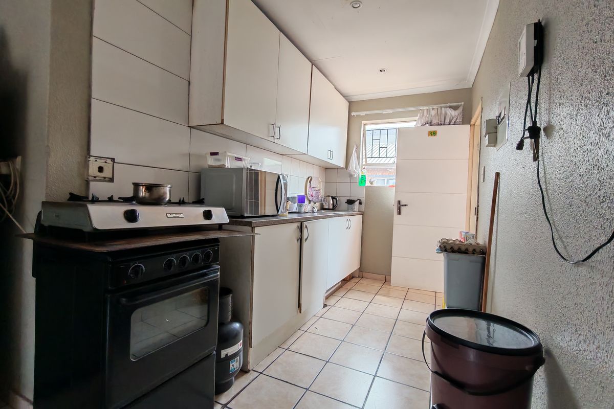 A functional kitchen featuring built-in cabinetry, tiled splashbacks, and a gas stove, offering a practical layout with potential for cosmetic updates.