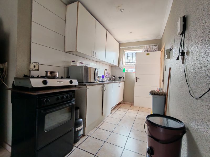 A functional kitchen featuring built-in cabinetry, tiled splashbacks, and a gas stove, offering a practical layout with potential for cosmetic updates.