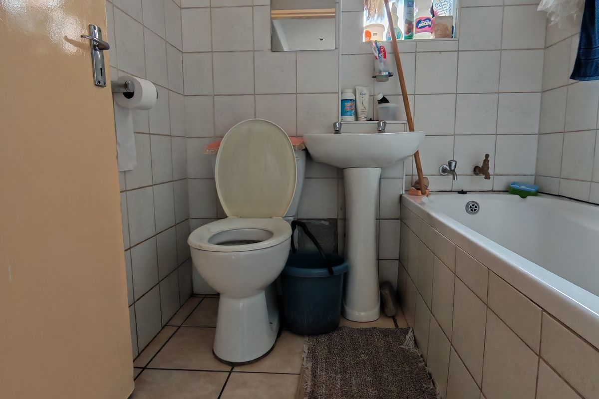 A functional bathroom featuring a pedestal basin, toilet, and bathtub with tiled finishes throughout.