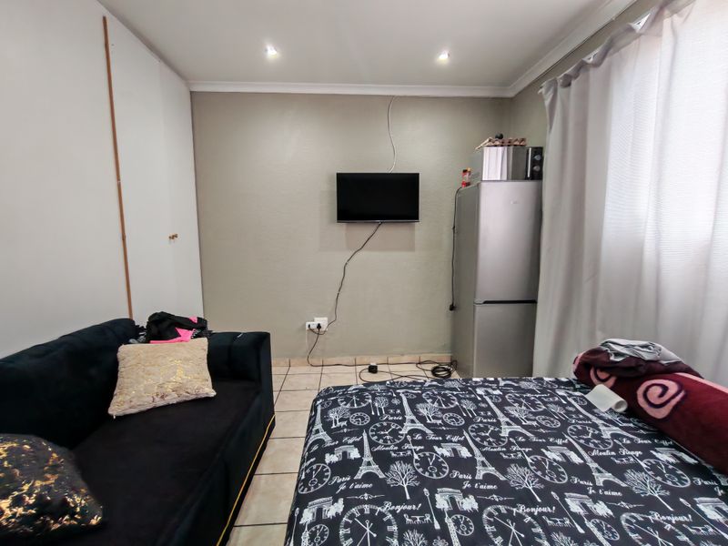 A bedroom featuring tiled flooring, built-in cupboards, and recessed downlighting, offering a functional space with potential for cosmetic updates.