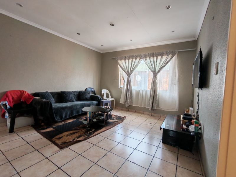 A living room featuring tiled flooring and recessed downlights, offering a functional space with neutral wall tones.