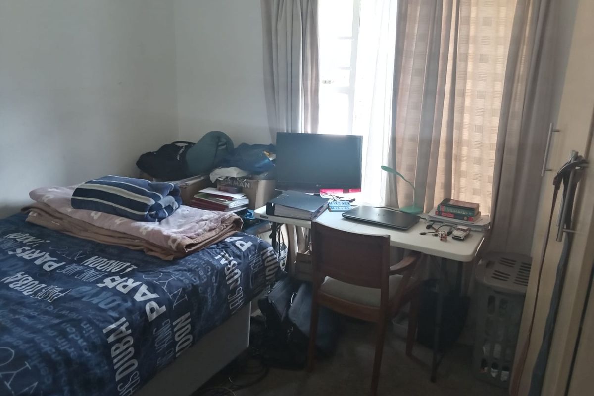 A functional bedroom featuring a window with curtains and built-in cupboard space.
