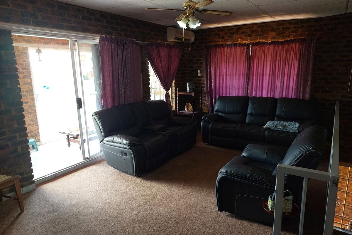Spacious living room featuring exposed brick walls, a ceiling fan, and large sliding glass doors providing access to the outdoor area.