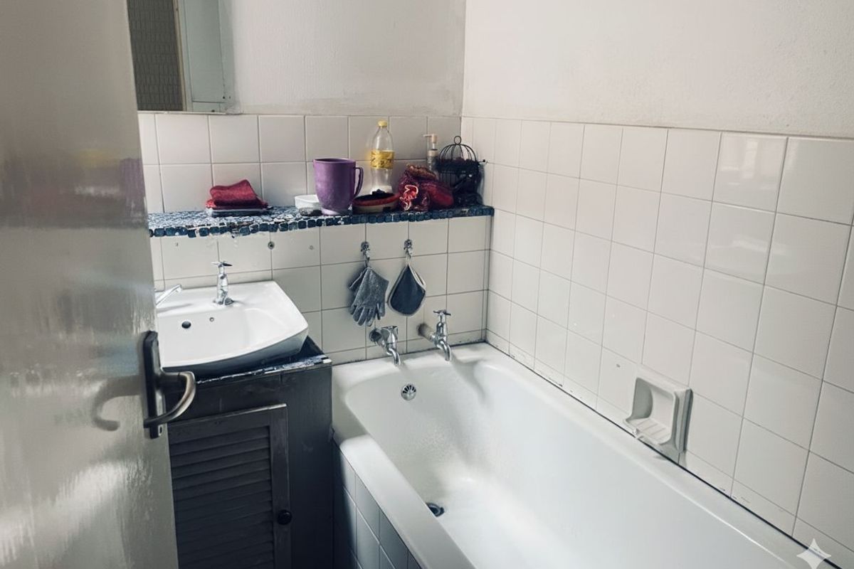 Compact bathroom featuring a white bathtub, wall-mounted basin, and tiled splashback areas with a built-in vanity ledge.