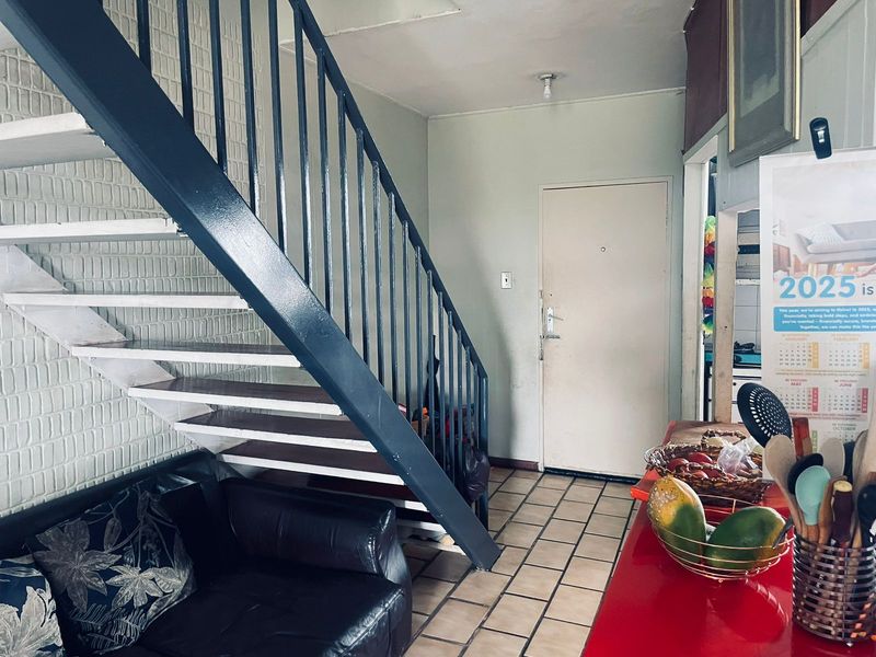 Interior view of an entrance area featuring a painted metal staircase, tiled flooring, and direct access to the living space.