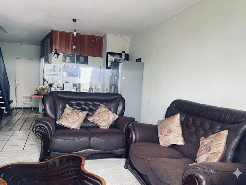 Open plan living area featuring tiled flooring and a staircase, seamlessly connecting to the kitchen space.