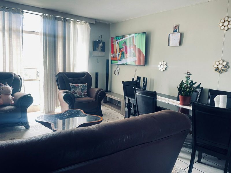 Open plan living and dining area featuring tiled flooring and large glass sliding doors providing natural light.