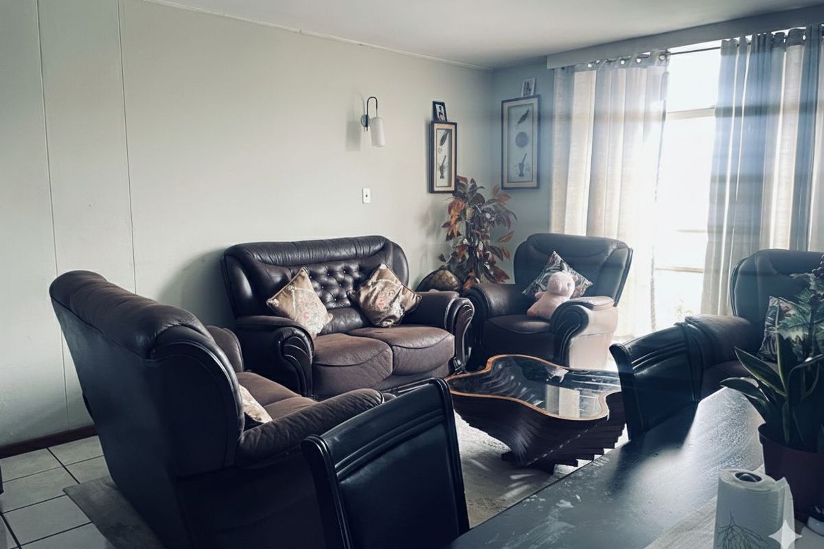 A comfortable living room area featuring tiled flooring and natural light from the adjacent window.