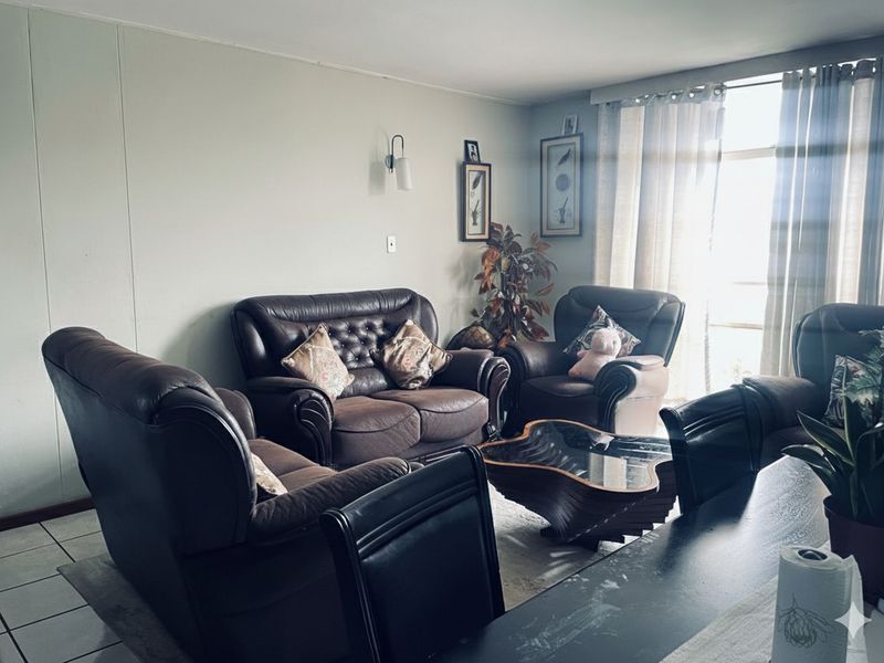 A comfortable living room area featuring tiled flooring and natural light from the adjacent window.