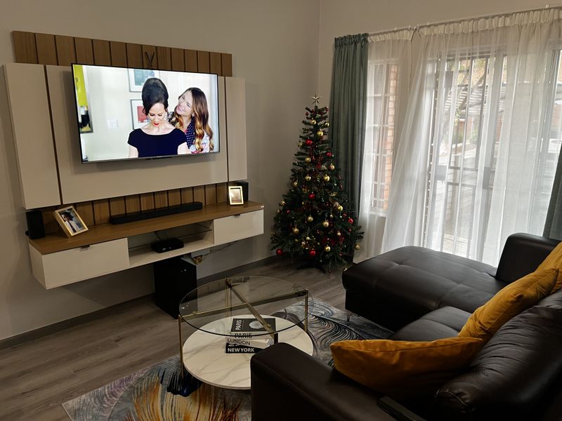 A modern living room featuring a built-in media wall unit, laminate flooring, and large sliding glass doors leading to an outdoor area.