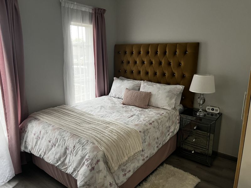 A well-maintained bedroom featuring laminate flooring and a window with natural light.
