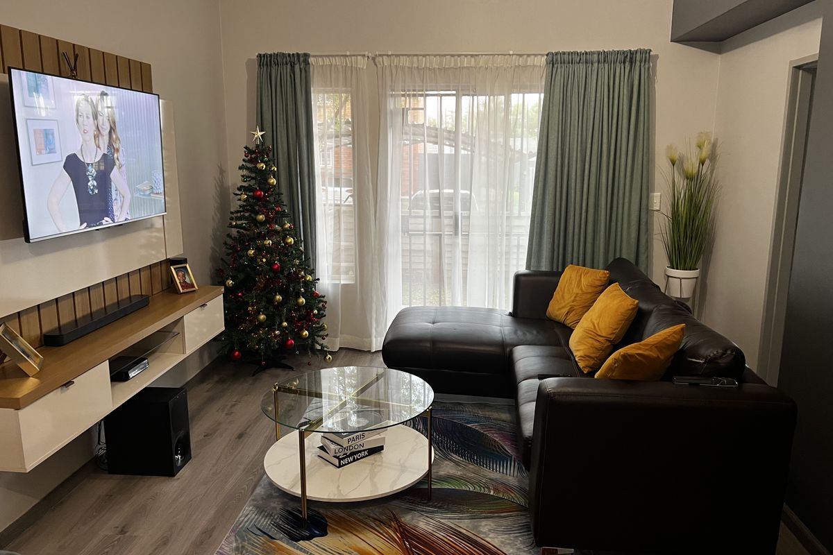 A well-maintained living room featuring modern wood-look flooring, a built-in media console, and sliding glass doors leading to an outdoor area.