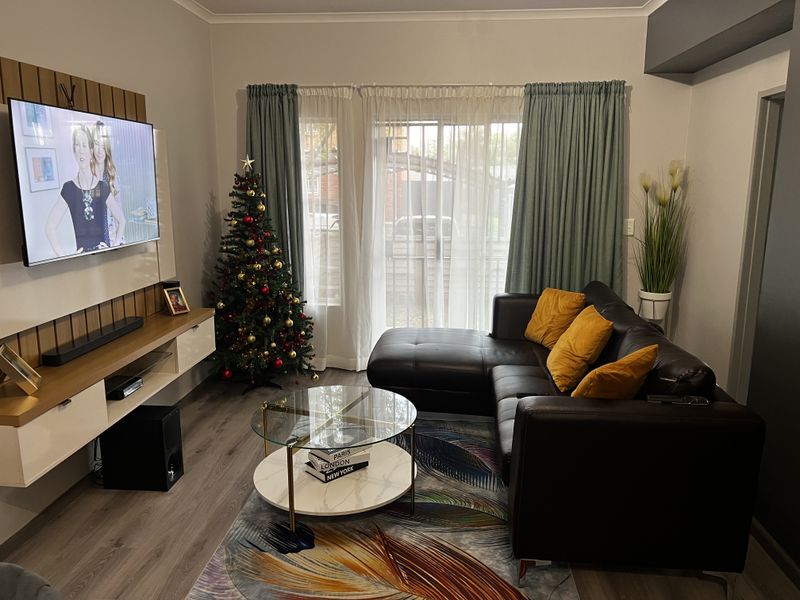 A well-maintained living room featuring modern wood-look flooring, a built-in media console, and sliding glass doors leading to an outdoor area.