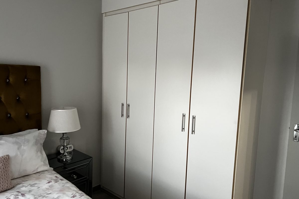A bedroom featuring a large, white built-in wardrobe with modern silver handles, providing ample storage space.