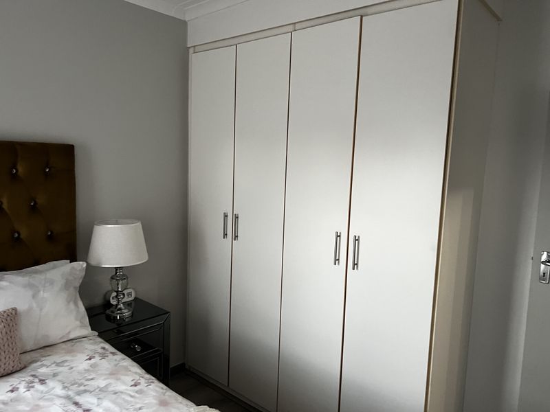 A bedroom featuring a large, white built-in wardrobe with modern silver handles, providing ample storage space.