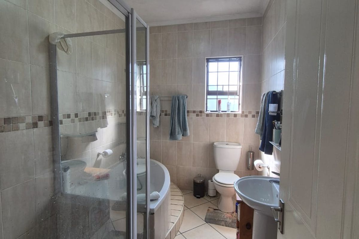 A functional bathroom featuring a glass-enclosed shower, a separate bathtub, a pedestal basin, and a toilet with tiled walls and flooring.