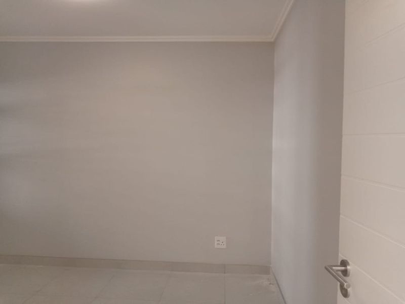 A clean, neutral-toned interior space featuring tiled flooring and a modern internal door, suitable for use as a bedroom or living area.