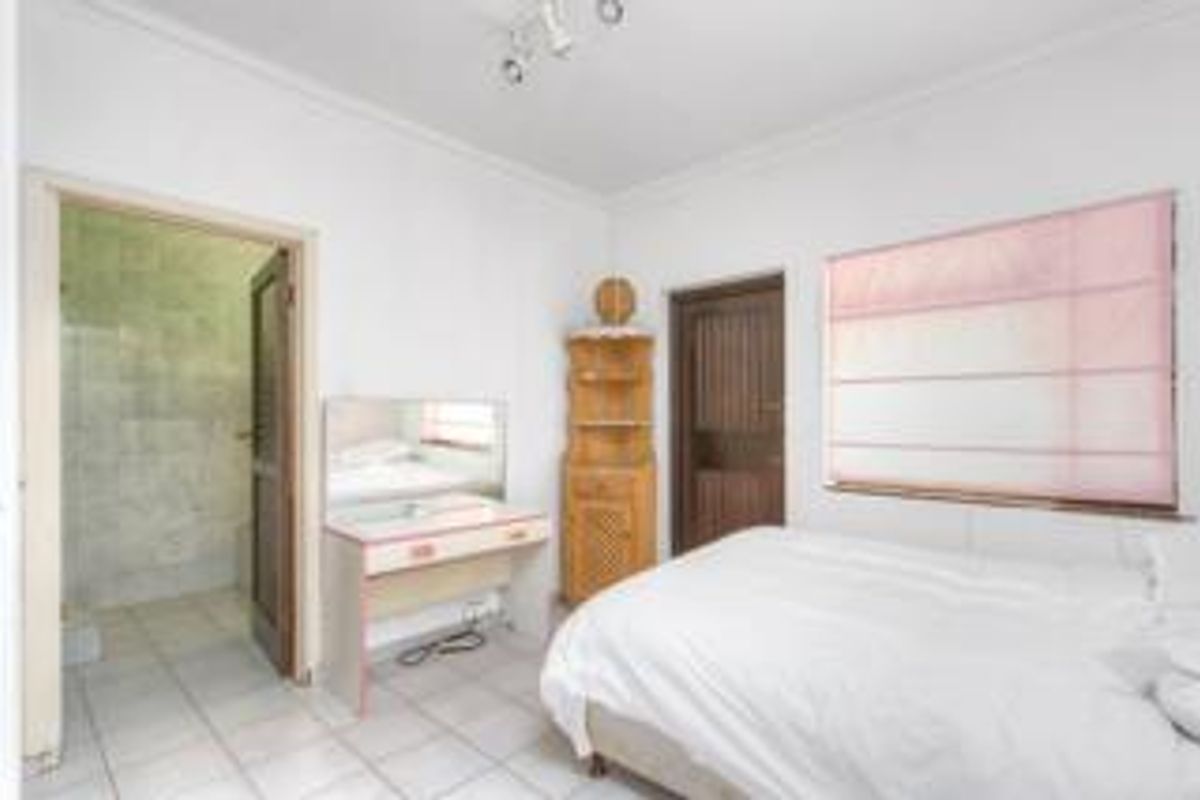 A functional bedroom featuring tiled flooring, a built-in vanity area, and an en-suite bathroom access point.