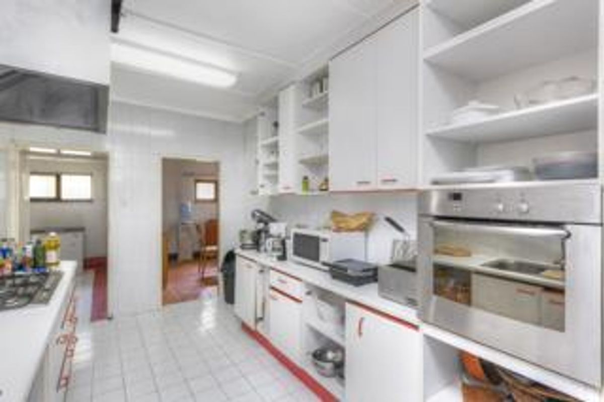 Functional kitchen featuring white cabinetry, built-in oven, gas hob, and tiled flooring, with an adjacent scullery area.