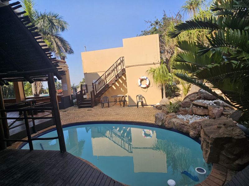 Outdoor pool area featuring a swimming pool, timber decking, stone water feature, and an external staircase leading to an upper level.