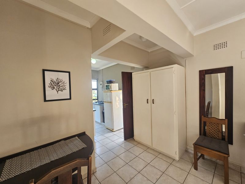 Open plan living area featuring tiled flooring, a built-in cupboard, and an archway leading to the kitchen area.