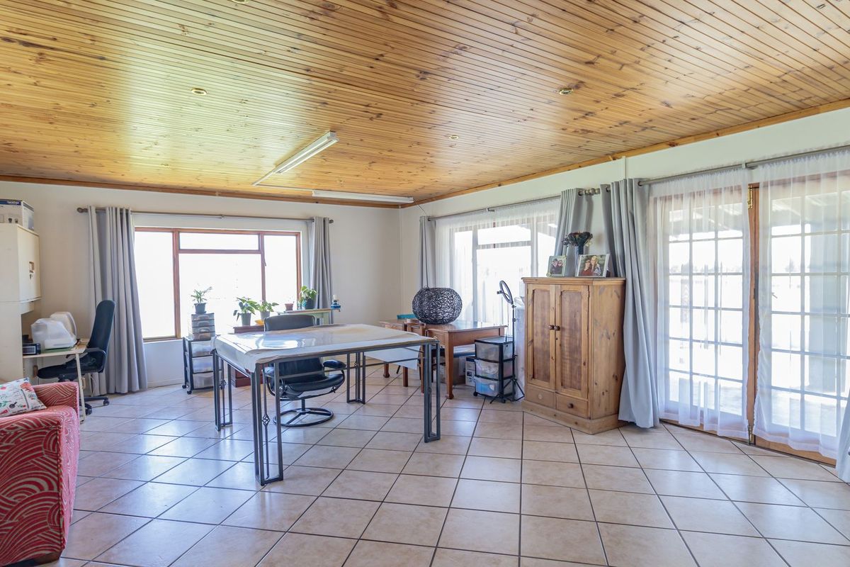 Spacious living area featuring a timber tongue and groove ceiling, ceramic tiled flooring, and direct access to the outdoors through glass french doors.