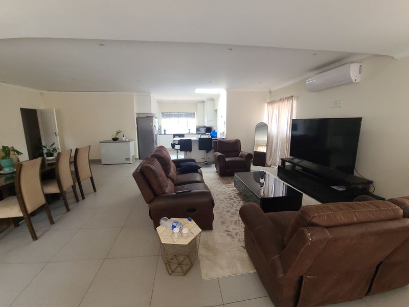 Spacious open-plan living area featuring tiled floors, a modern kitchen island, and a wall-mounted split-system air conditioner.