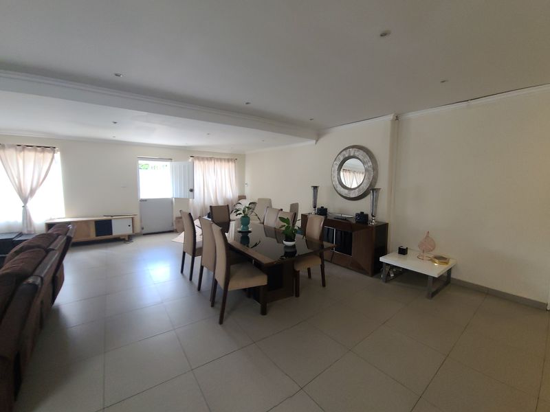 Spacious open-plan living and dining area featuring neutral tiled flooring, recessed downlighting, and a coved ceiling, providing a versatile layout for family living.
