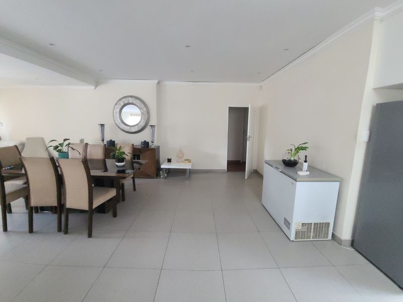 Spacious dining area featuring neutral tiled flooring, recessed ceiling lighting, and decorative cornicing, providing a versatile space for family meals and entertaining.