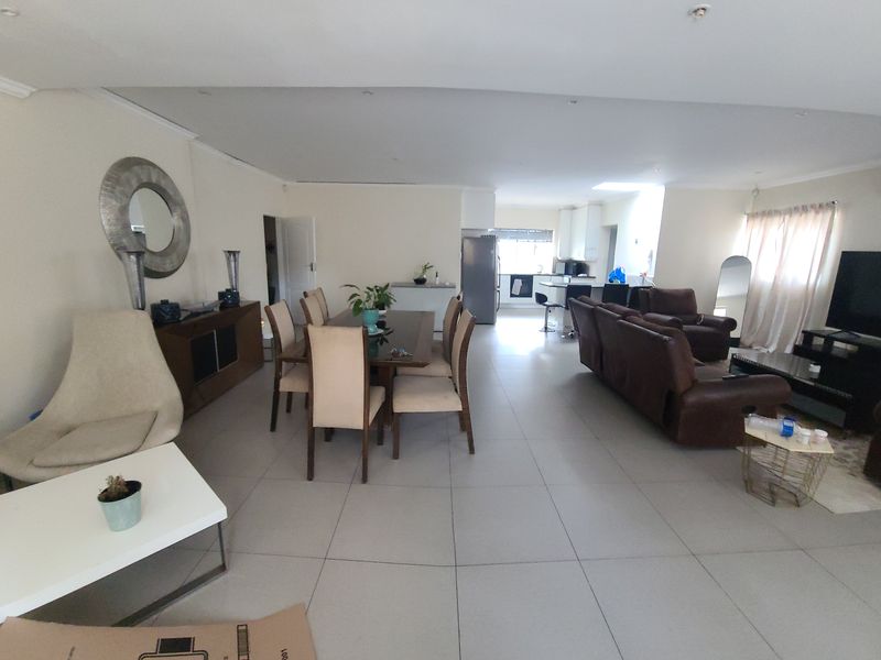 Spacious open-plan living and dining area featuring large format floor tiles, recessed lighting, and a seamless flow into the modern kitchen space.