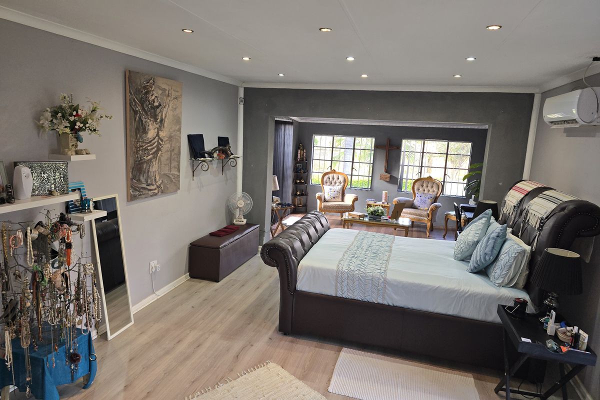 Spacious bedroom featuring light wood-look flooring, recessed ceiling lighting, and an integrated air conditioning unit.
