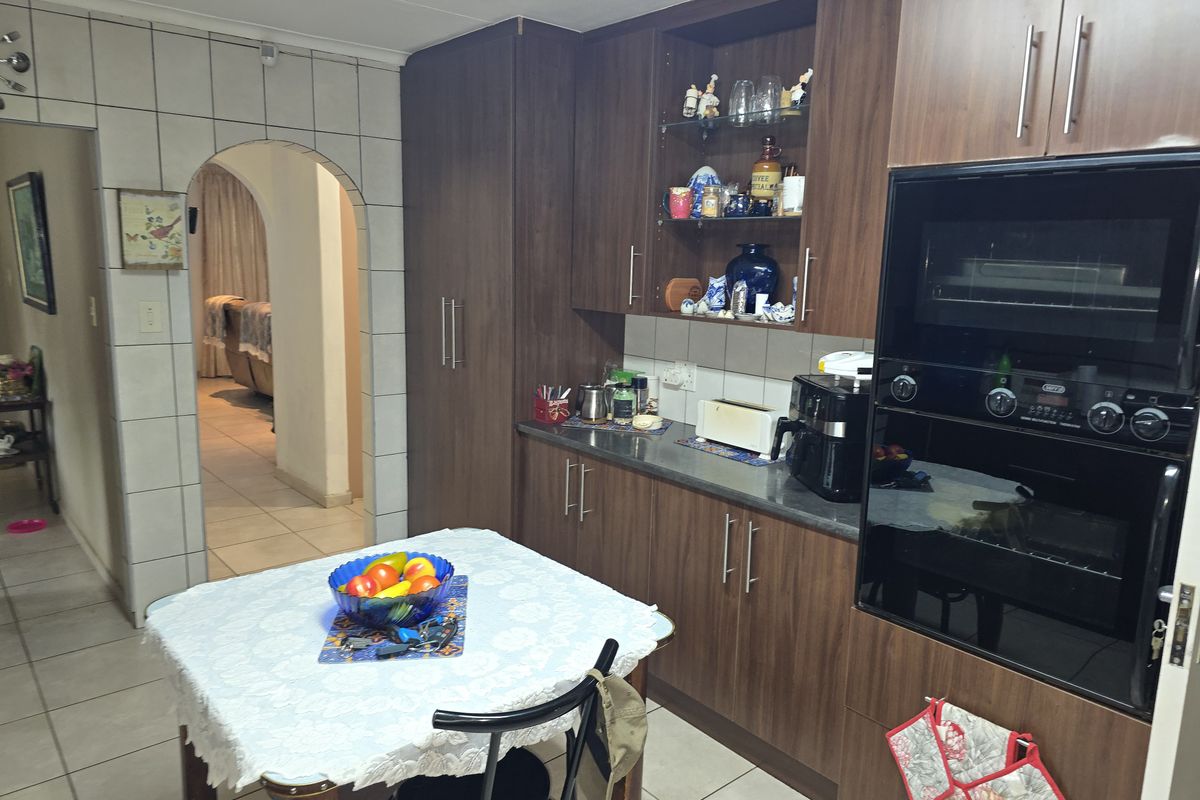 Kitchen featuring dark wood cabinetry, built-in oven, and tiled flooring, with an arched entryway leading to the adjacent living area.