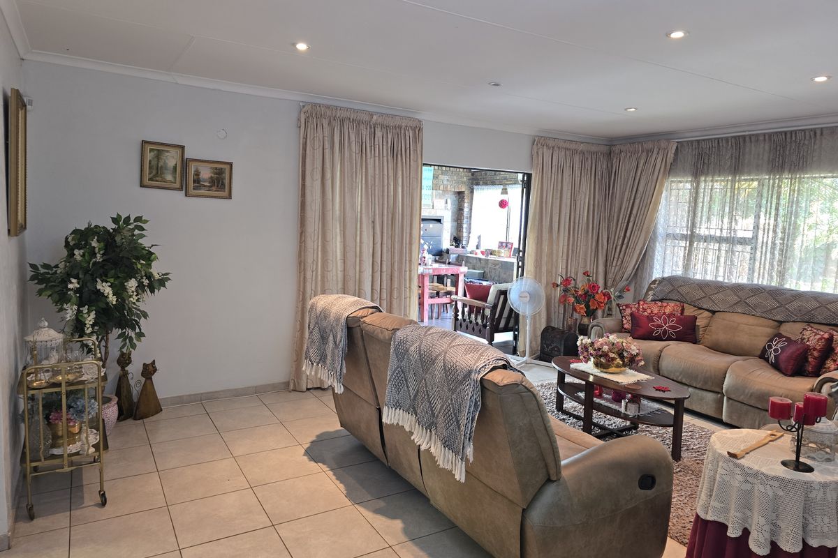 Spacious living room featuring tiled flooring, recessed ceiling lighting, and large sliding doors providing direct access to an outdoor patio area.