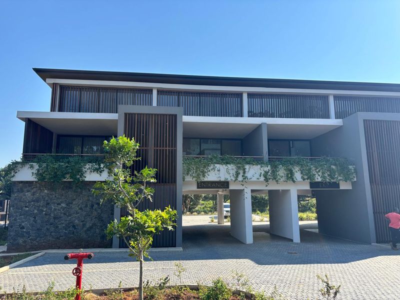 Modern townhouse exterior featuring stone cladding, timber louvres, and a covered entrance area with paved driveway access.
