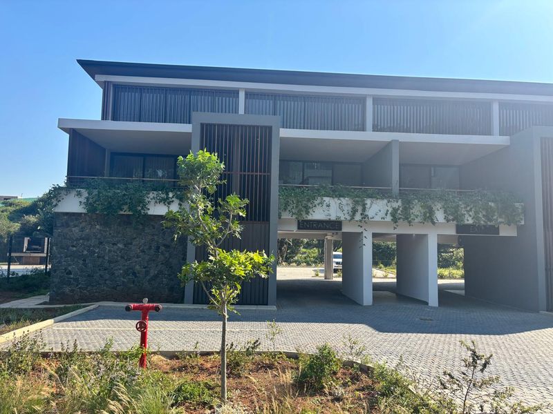Modern townhouse exterior featuring stone cladding, covered parking bays, and a balcony with timber screening.