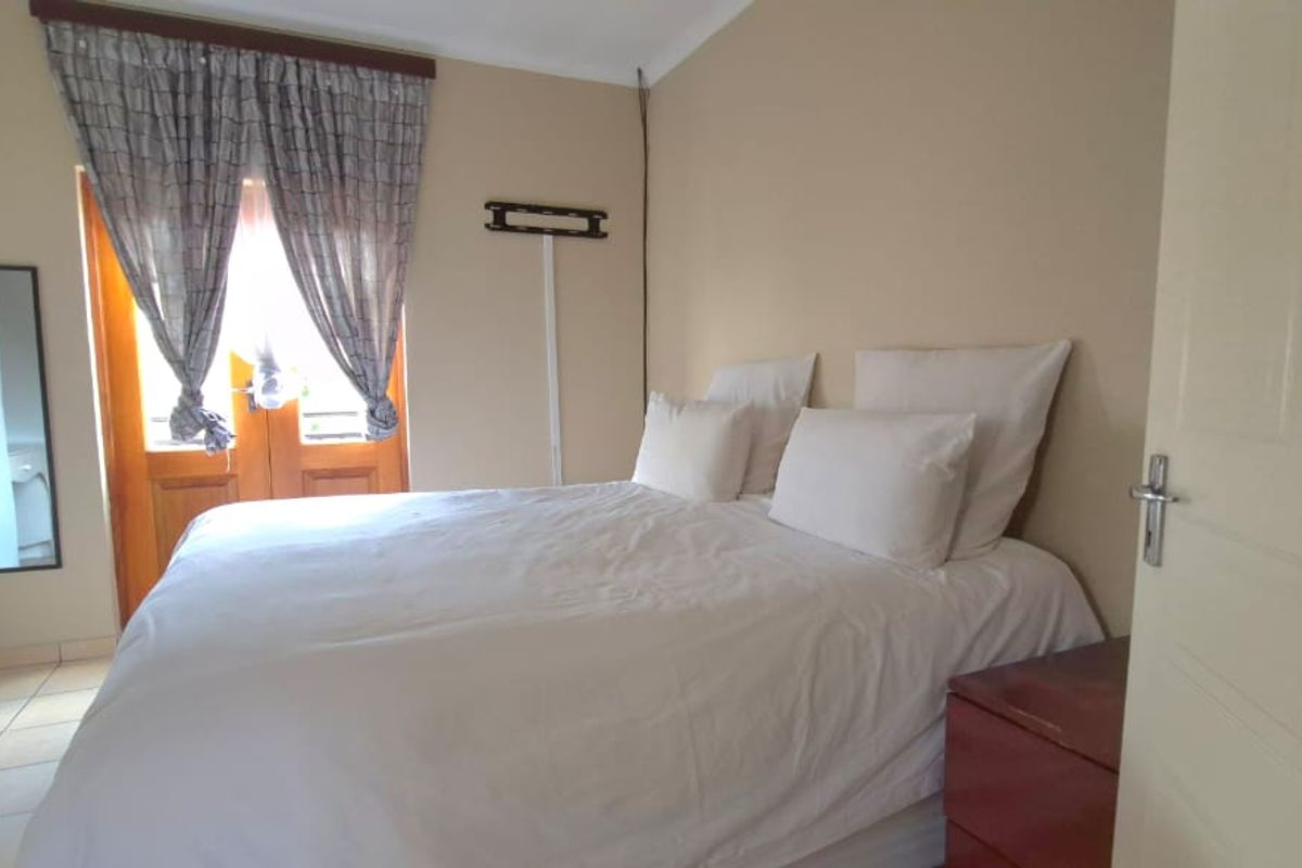A bedroom featuring built-in cupboards, tiled flooring, and double doors leading to an outdoor area.