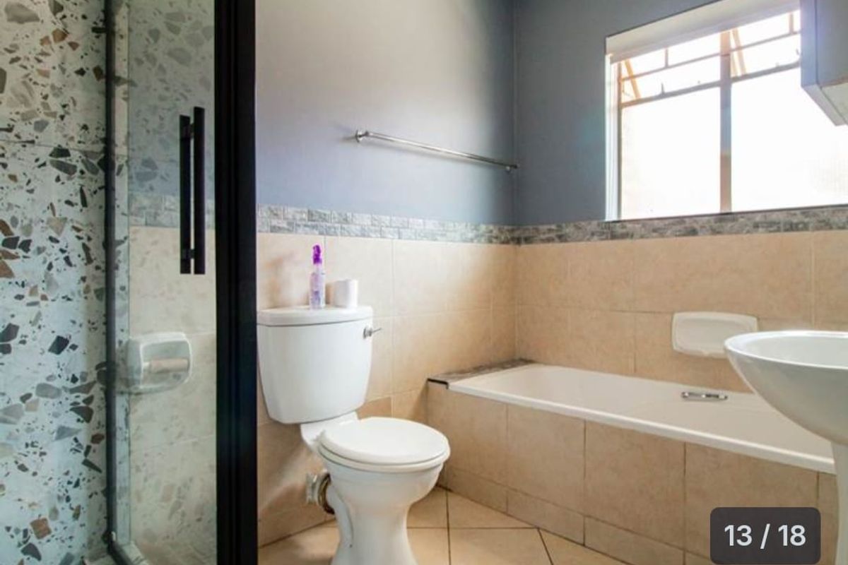 A functional bathroom featuring a built-in bathtub, a separate shower enclosure with terrazzo-style tiling, a toilet, and a pedestal basin.