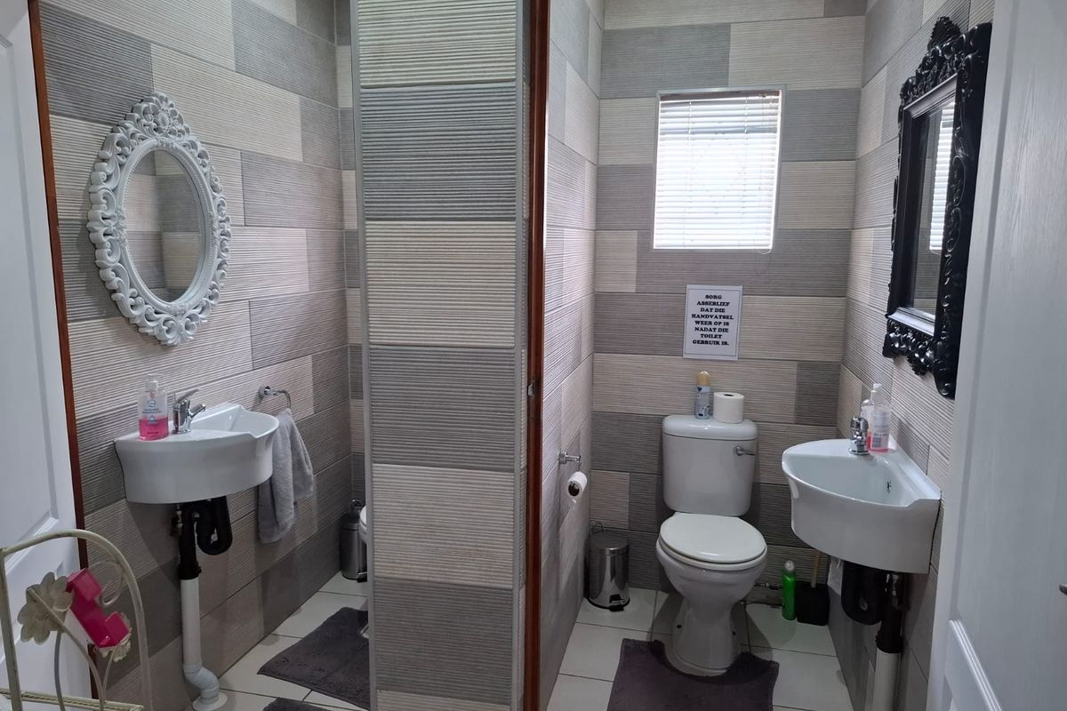 A functional bathroom featuring dual wall-mounted basins, a toilet, and modern horizontal-patterned wall tiling.