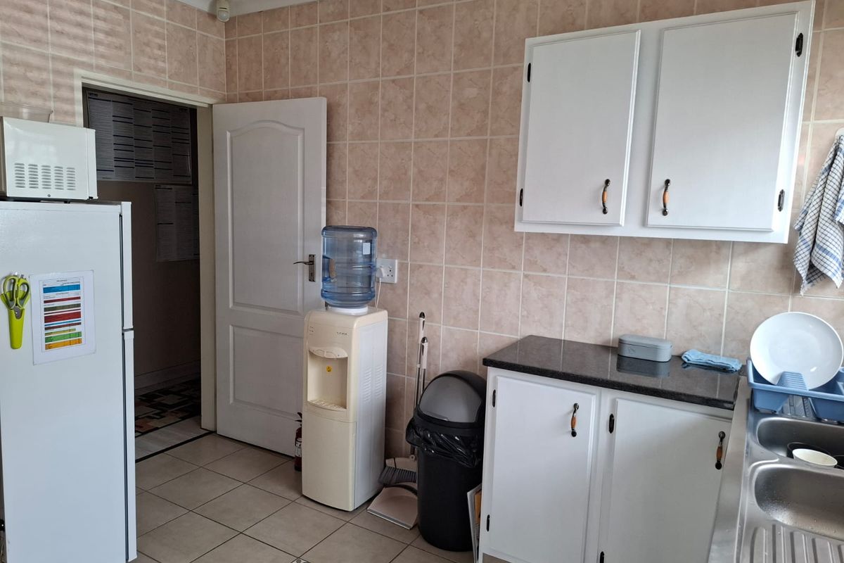 A functional kitchen area featuring white cabinetry, dark countertops, and tiled wall finishes, providing a practical workspace for daily food preparation.