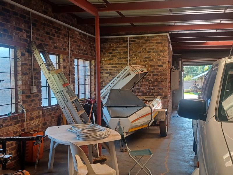 Spacious garage featuring exposed brick walls, steel beam ceiling structure, and large steel-framed windows, providing ample storage or workshop potential.
