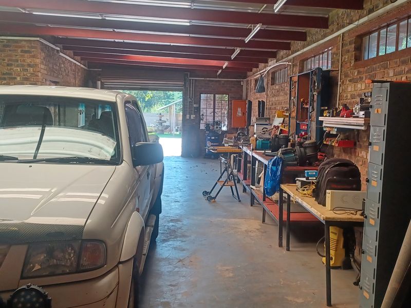 Spacious garage featuring exposed brick walls, steel beam ceiling structure, concrete flooring, and clerestory windows, providing ample room for vehicle storage and workshop activities.
