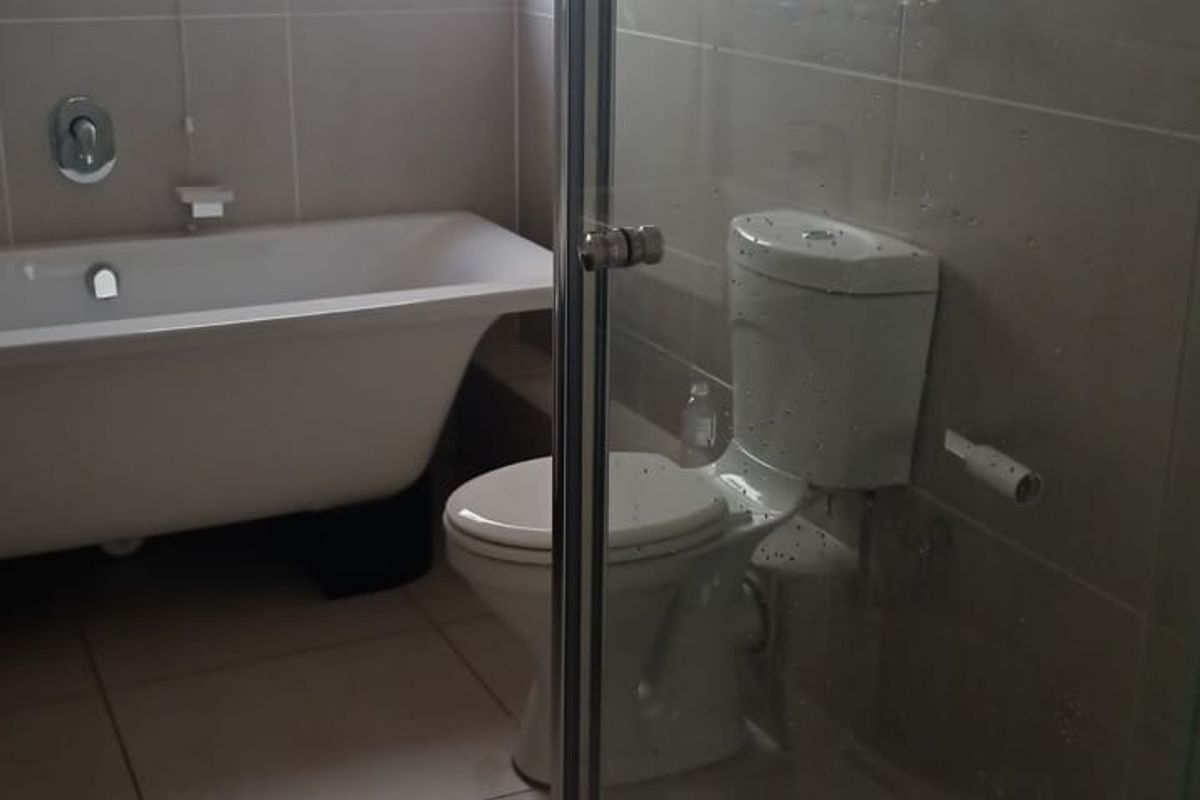 A modern bathroom featuring a freestanding bathtub, a separate glass-enclosed shower, and a toilet, finished with neutral wall and floor tiles.