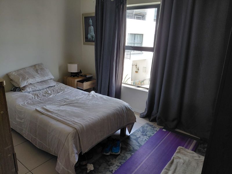 A functional bedroom featuring tiled flooring and a large window with natural light, suitable for a comfortable living space.
