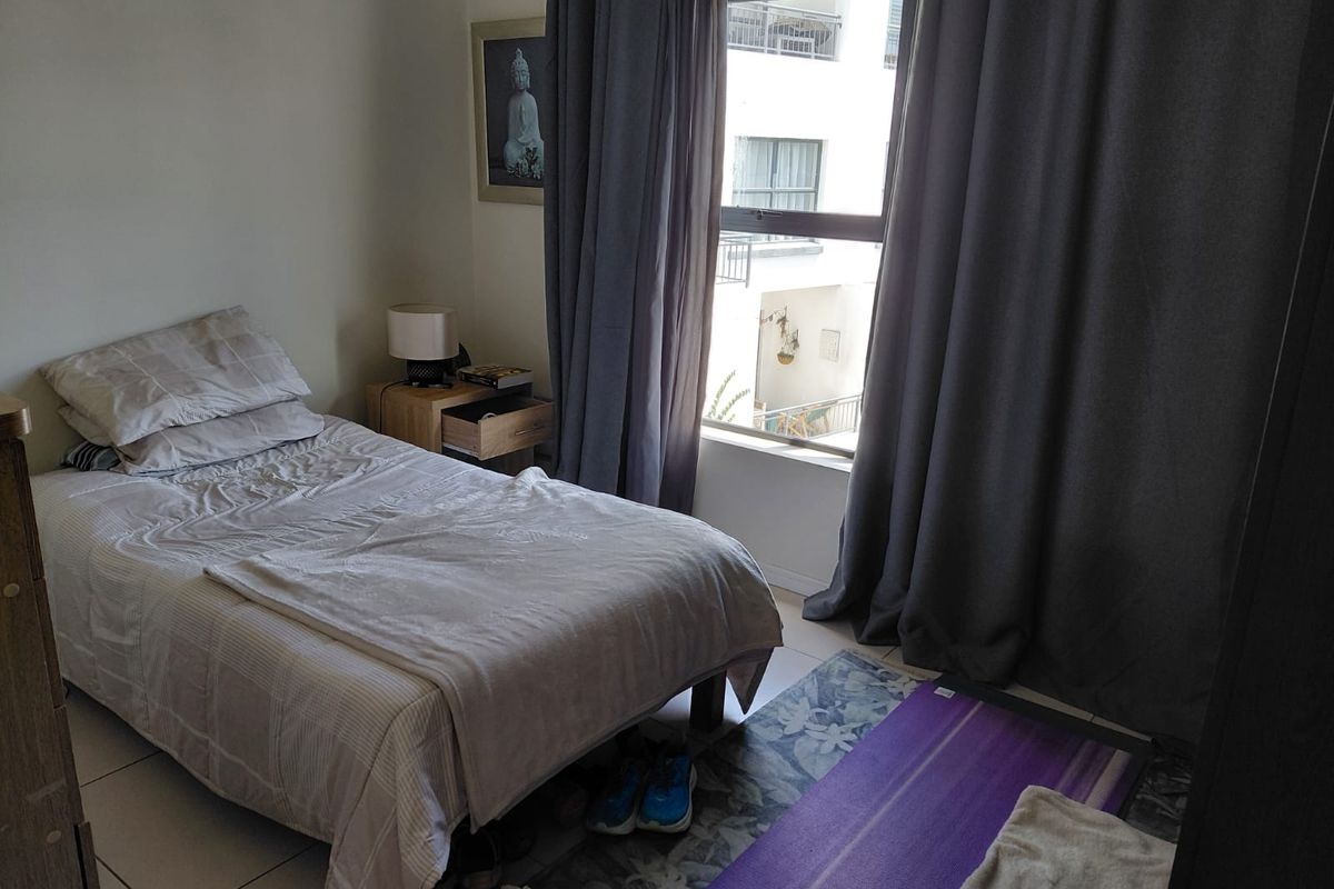 A functional bedroom featuring tiled flooring and a large window with natural light, suitable for a comfortable living space.