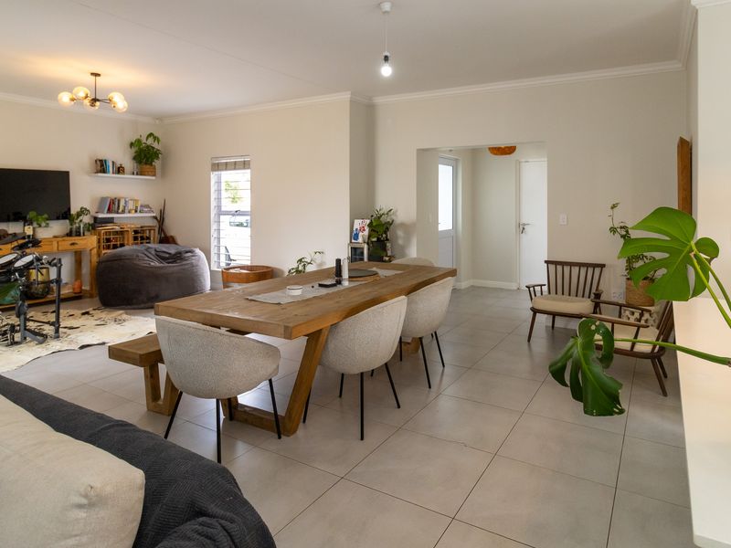Spacious open-plan living and dining area featuring neutral tiled flooring, clean wall finishes, and modern lighting, creating a bright and versatile living space.