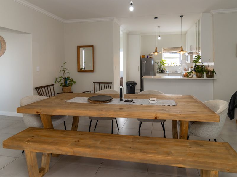 Spacious open-plan living and dining area featuring tiled floors, neutral walls, and a modern kitchen with a central island and pendant lighting.