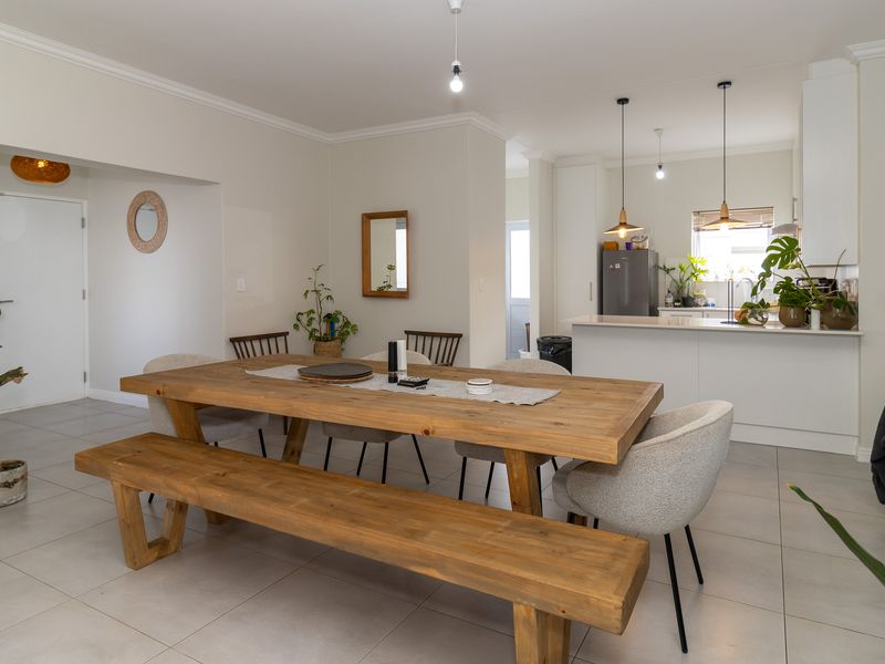 Spacious open-plan living and dining area featuring modern tiled flooring, neutral walls, and a functional kitchen with a central island and pendant lighting.