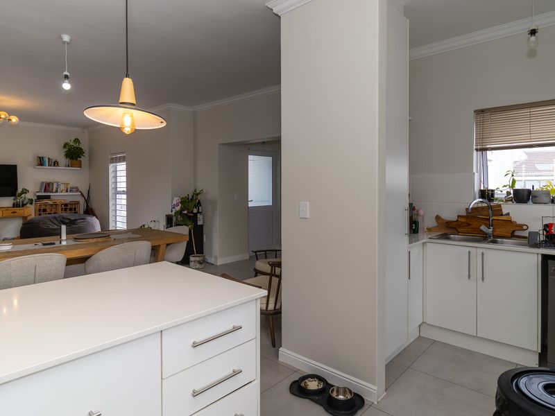 Open plan living area featuring a modern kitchen with white cabinetry, a central island, and tiled flooring, seamlessly flowing into the dining space.